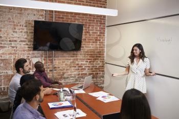 Businesswoman Standing By Whiteboard To Deliver Presentation