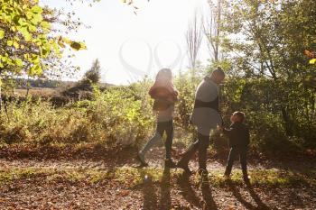 Family On Autumn Walk In Woodland Together