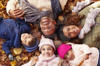 Overhead Portrait Of Family Lying In Autumn Leaves