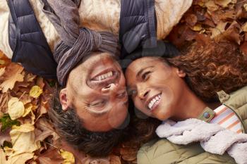 Overhead Portrait Of Couple Lying In Autumn Leaves