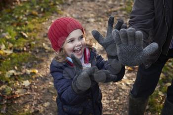Granddaughter Wearing Grandfather's Gloves On Autumn Walk