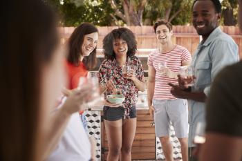 Young adult friends standing with drinks at a backyard party