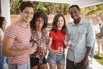Young adult friends at a backyard party, looking to camera