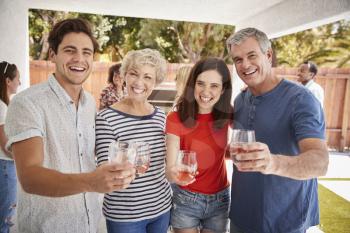 Parents and adult children raise glasses to camera in garden