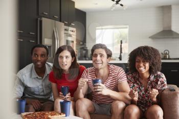 Four young adult friends watching sports on TV at home