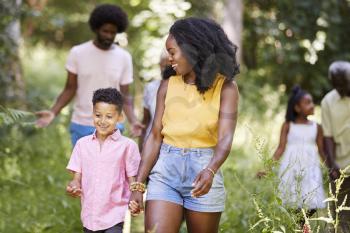 Black mother and son walk with family and friends in woods