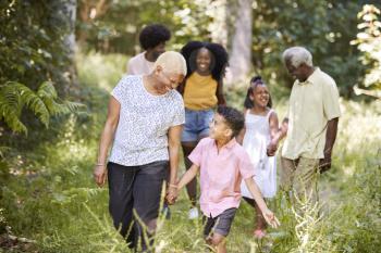 Senior black woman walking with grandson and family in woods