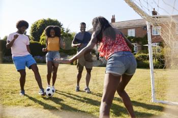 Black adult friends having a fun game of football in garden
