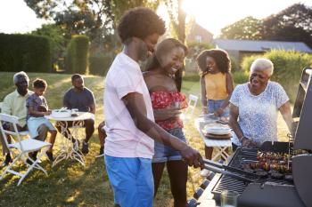 Couple grilling at a black multi generation family barbecue