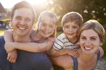 Portrait Of Smiling Family Outdoors In Summer Park Against Flaring Sun