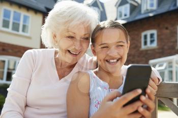 Granddaughter Showing Grandmother Mobile Phone On Visit To Retirement Home