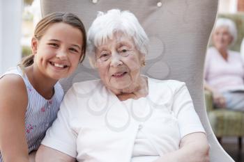 Portrait Of Granddaughter Visiting Grandmother In Retirement Home