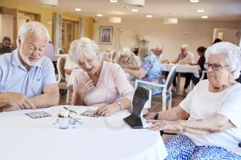 Group Of Seniors Playing Game Of Bingo In Retirement Home