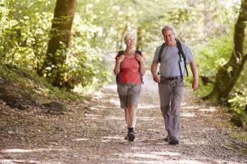 Senior Couple Hiking Along Woodland Path In Lake District UK Together