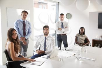 Portrait Of Businessmen And Businesswomen Meeting Around Table In Modern Boardroom