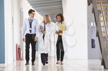 Three young male and female doctors walking in hospital