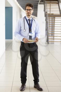 Portrait of a young male doctor holding notes, full length