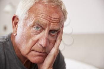 Senior Man Sitting On Bed At Home Suffering From Depression