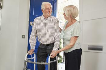 Senior couple at home talking, man using a walking frame
