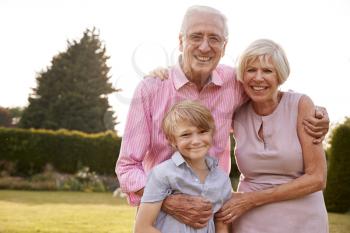 Senior couple and grandson embracing and smiling to camera