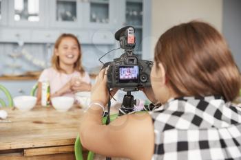 Girl filming her friend for cookery video blog in kitchen