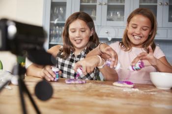 Two girls video blogging in kitchen preparing ingredients
