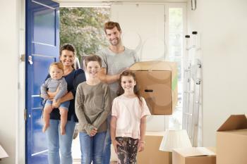 Portrait Of Family Carrying Boxes Into New Home On Moving Day