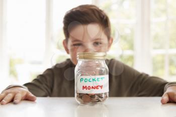 Boy Saving Pocket Money In Glass Jar At Home