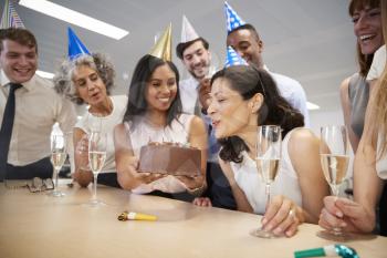 Woman blows out candles on birthday cake in office