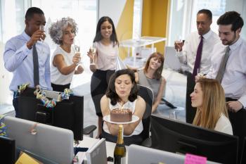 Colleagues gathered at womans desk to celebrate a birthday