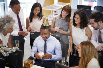 Colleagues gathered at a mans desk to celebrate a birthday