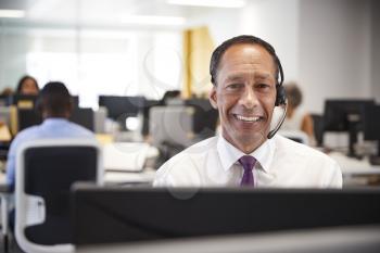 Middle aged man working at computer with headset in office
