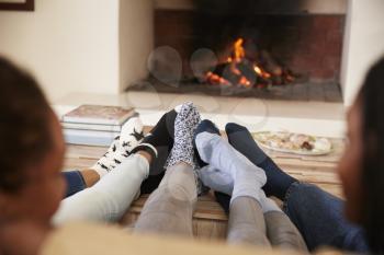 Close Up Of Feet As Family Relax Next To Open Fire