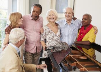 Group Of Seniors Standing By Piano And Singing Together