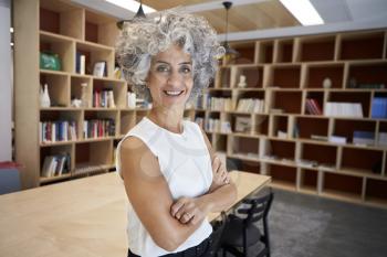 Senior businesswoman standing in boardroom smiling to camera