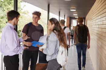 Teenage Students Talking To Teacher Outside School Buildings