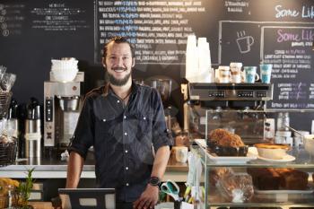 Portrait Of Male Barista Behind Counter In Coffee Shop