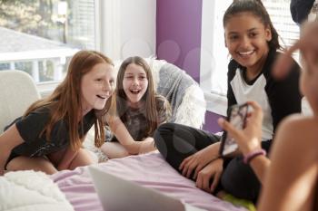 Four teen girls in bedroom looking at smartphone, close up