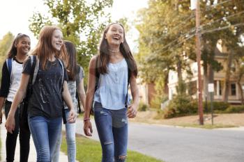 Four young teen girls walking to school, front view close up