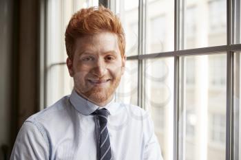 Young red haired bearded businessman smiling to camera
