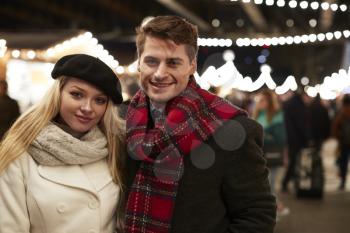 Portrait Of Couple Enjoying Christmas Market At Night