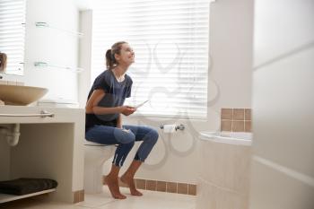 Woman In Bathroom Celebrates Positive Home Pregnancy Test Result