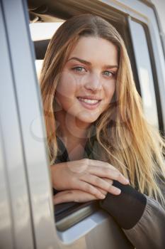 Young white woman looking to camera from open window of car