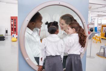 Schoolgirls looking in a magnifying mirror at science centre