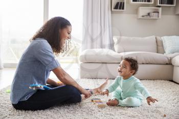 Mixed race mum and toddler son playing in sitting room