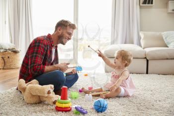 Father and young daughter playing toy instruments at home