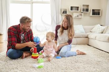 Young parents and toddler daughter playing in sitting room