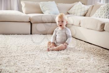 White toddler boy sitting on the floor in sitting room