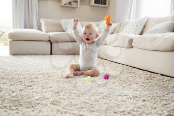 White toddler boy on the floor in sitting room raising arms