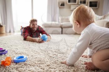 Young father playing with toddler son on the floor at  home